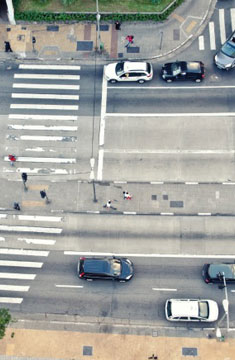 Bird's Eye View Of A Public Roadway With Cars Passing By and People Walking On The Sidewalk  