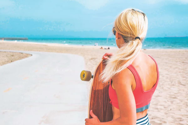 Woman with travel insurance skateboards along beach